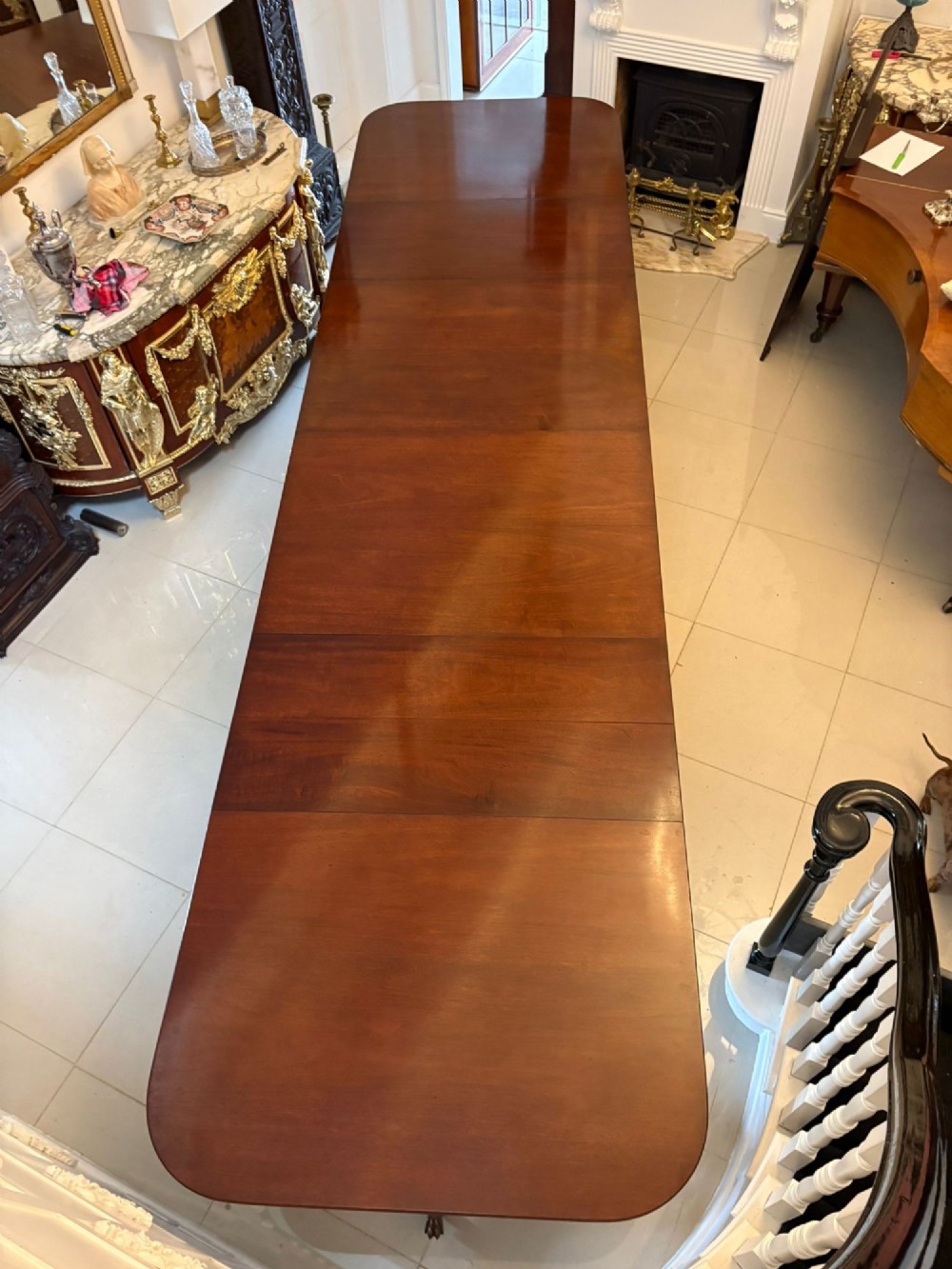 A long extendable mahogany banquet dining table set on four turned pedestal bases with splayed legs and brass castors. View XI