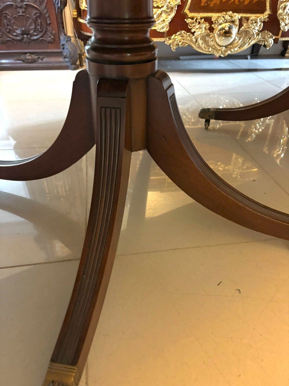 A long extendable mahogany banquet dining table set on four turned pedestal bases with splayed legs and brass castors. View XII