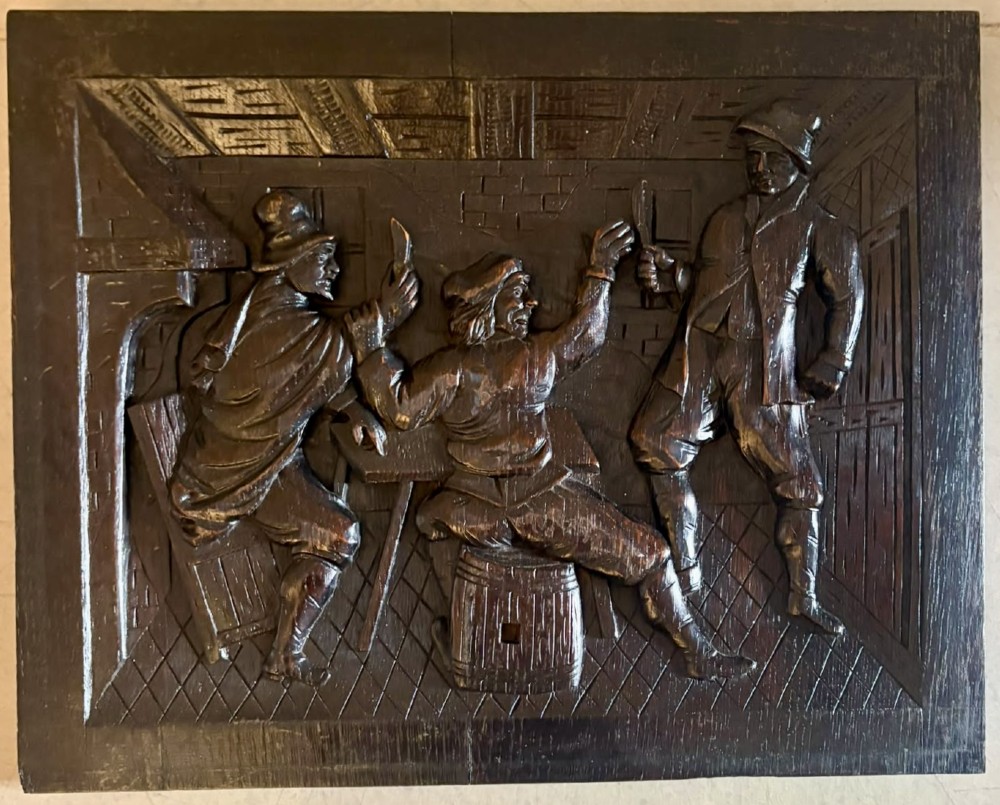 A set of five square dark carved oak wall panels featuring detailed bas-relief scenes of figures in traditional Flemish tavern settings. View IV
