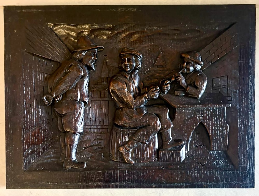 A set of five square dark carved oak wall panels featuring detailed bas-relief scenes of figures in traditional Flemish tavern settings. View V