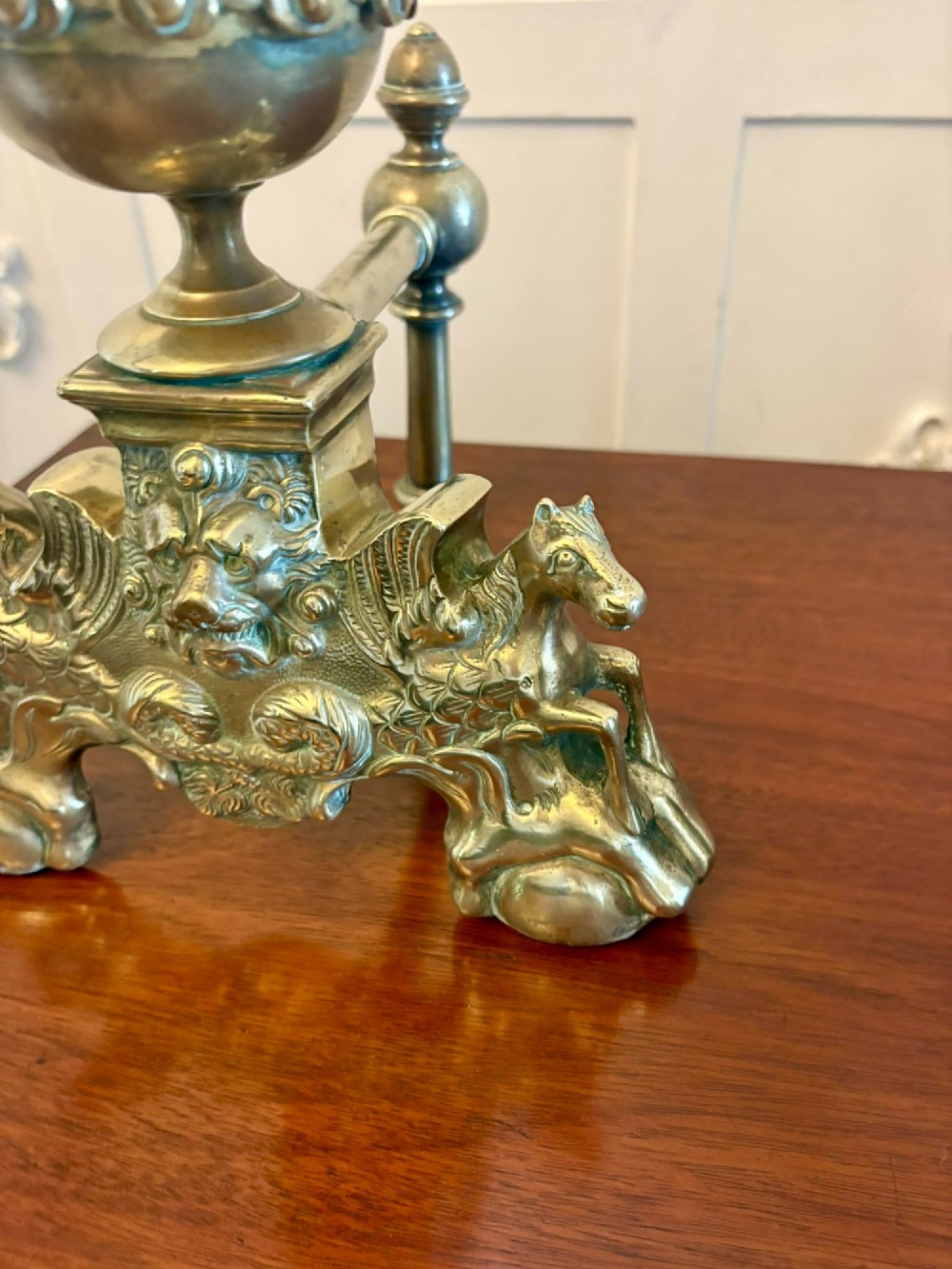 A pair of ornate Victorian cast brass fire dogs featuring spiral-fluted finials, gadrooned central urns, and mythological horse motifs on the base. View V