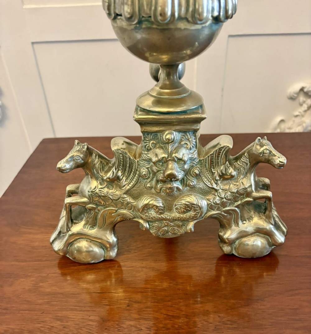 A pair of ornate Victorian cast brass fire dogs featuring spiral-fluted finials, gadrooned central urns, and mythological horse motifs on the base. View VII