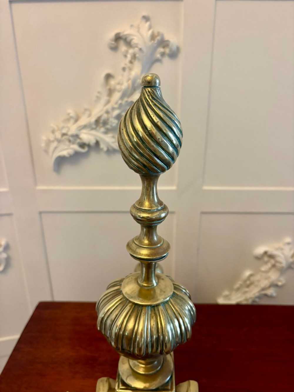 A pair of ornate Victorian cast brass fire dogs featuring spiral-fluted finials, gadrooned central urns, and mythological horse motifs on the base. View IX