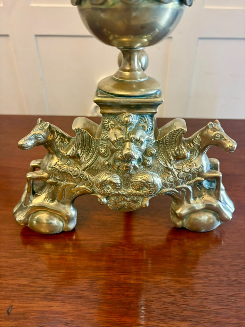 A pair of ornate Victorian cast brass fire dogs featuring spiral-fluted finials, gadrooned central urns, and mythological horse motifs on the base. View XI
