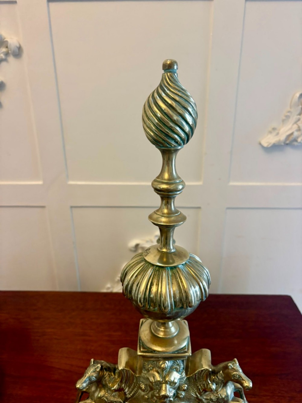 A pair of ornate Victorian cast brass fire dogs featuring spiral-fluted finials, gadrooned central urns, and mythological horse motifs on the base. View XII