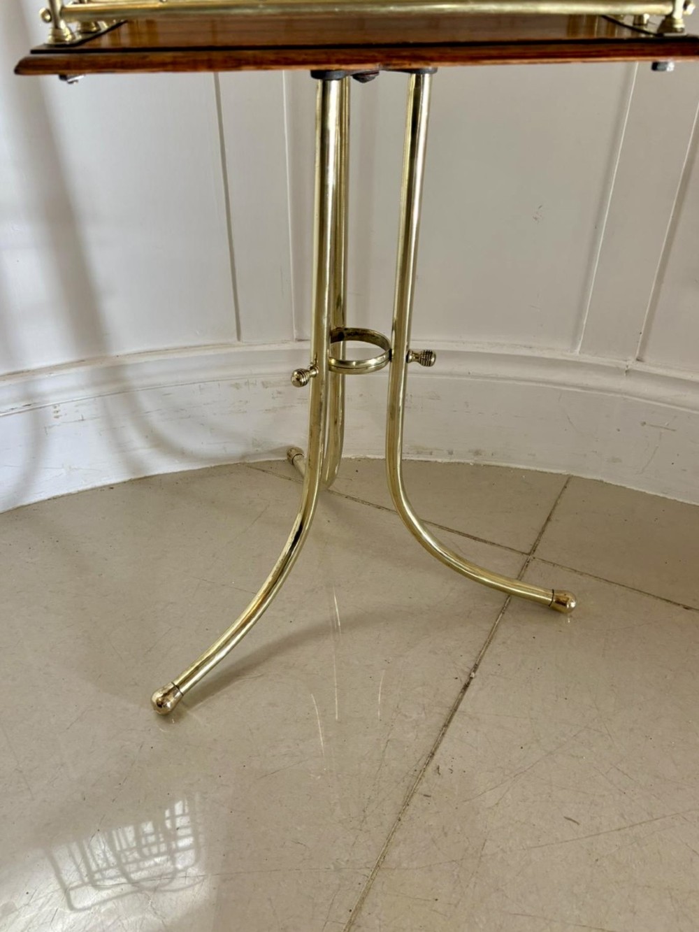 An antique Victorian brass magazine rack with divided wire compartments set upon a polished rectangular oak base and a curved brass tripod stand. View III