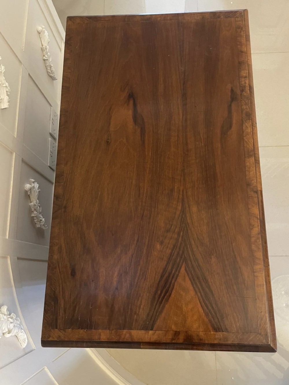 An early 18th-century George I walnut chest of drawers featuring burr walnut veneers, brass drop handles, keyhole escutcheons, and bracket feet. View II