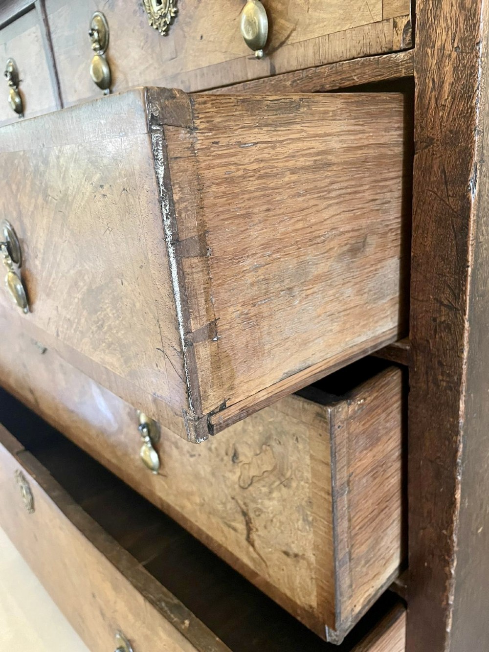 An early 18th-century George I walnut chest of drawers featuring burr walnut veneers, brass drop handles, keyhole escutcheons, and bracket feet. View III