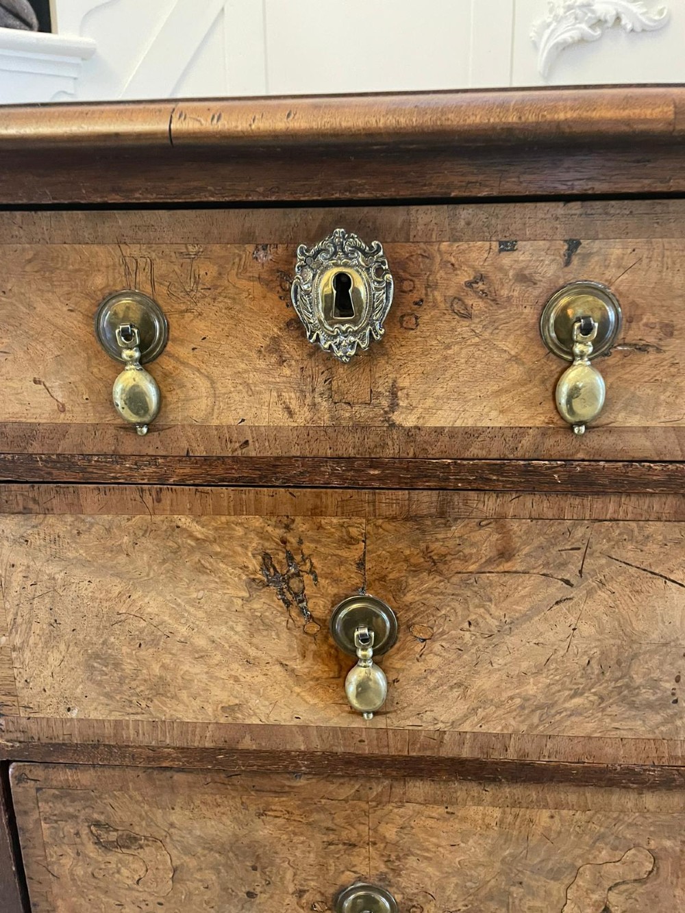 An early 18th-century George I walnut chest of drawers featuring burr walnut veneers, brass drop handles, keyhole escutcheons, and bracket feet. View IV
