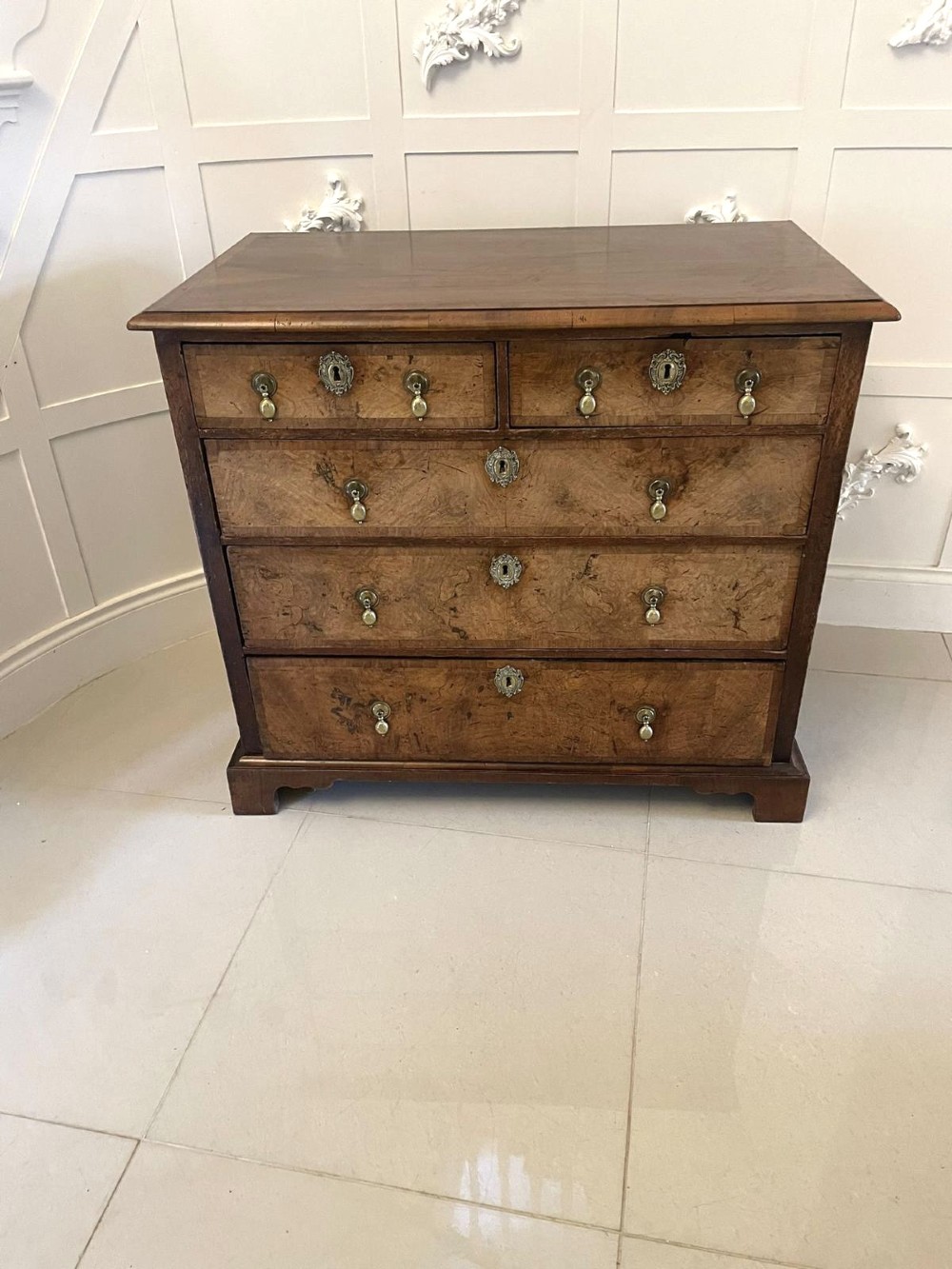 An early 18th-century George I walnut chest of drawers featuring burr walnut veneers, brass drop handles, keyhole escutcheons, and bracket feet. View VII