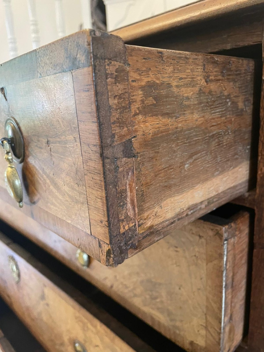 An early 18th-century George I walnut chest of drawers featuring burr walnut veneers, brass drop handles, keyhole escutcheons, and bracket feet. View IX