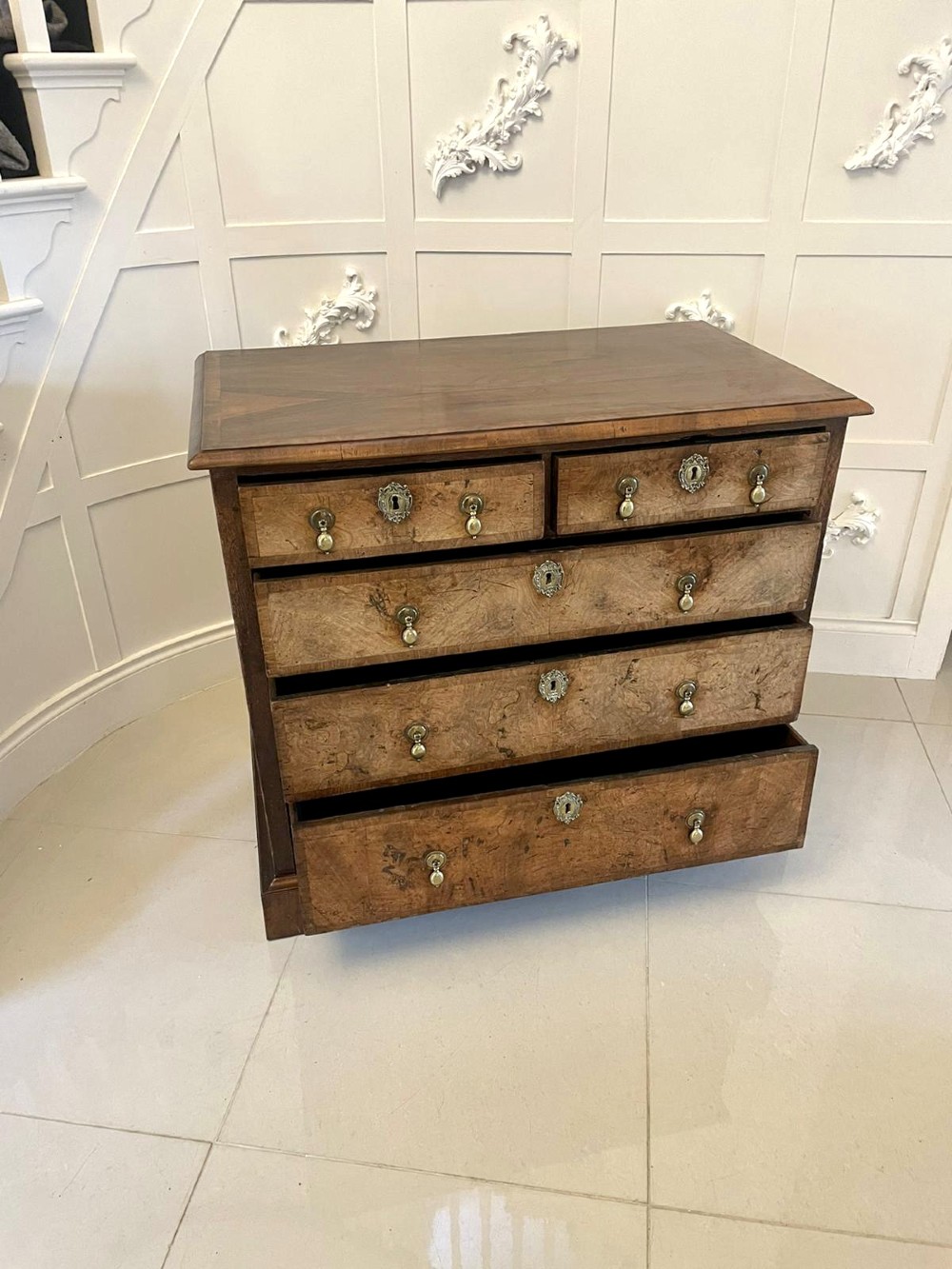 An early 18th-century George I walnut chest of drawers featuring burr walnut veneers, brass drop handles, keyhole escutcheons, and bracket feet. View XII