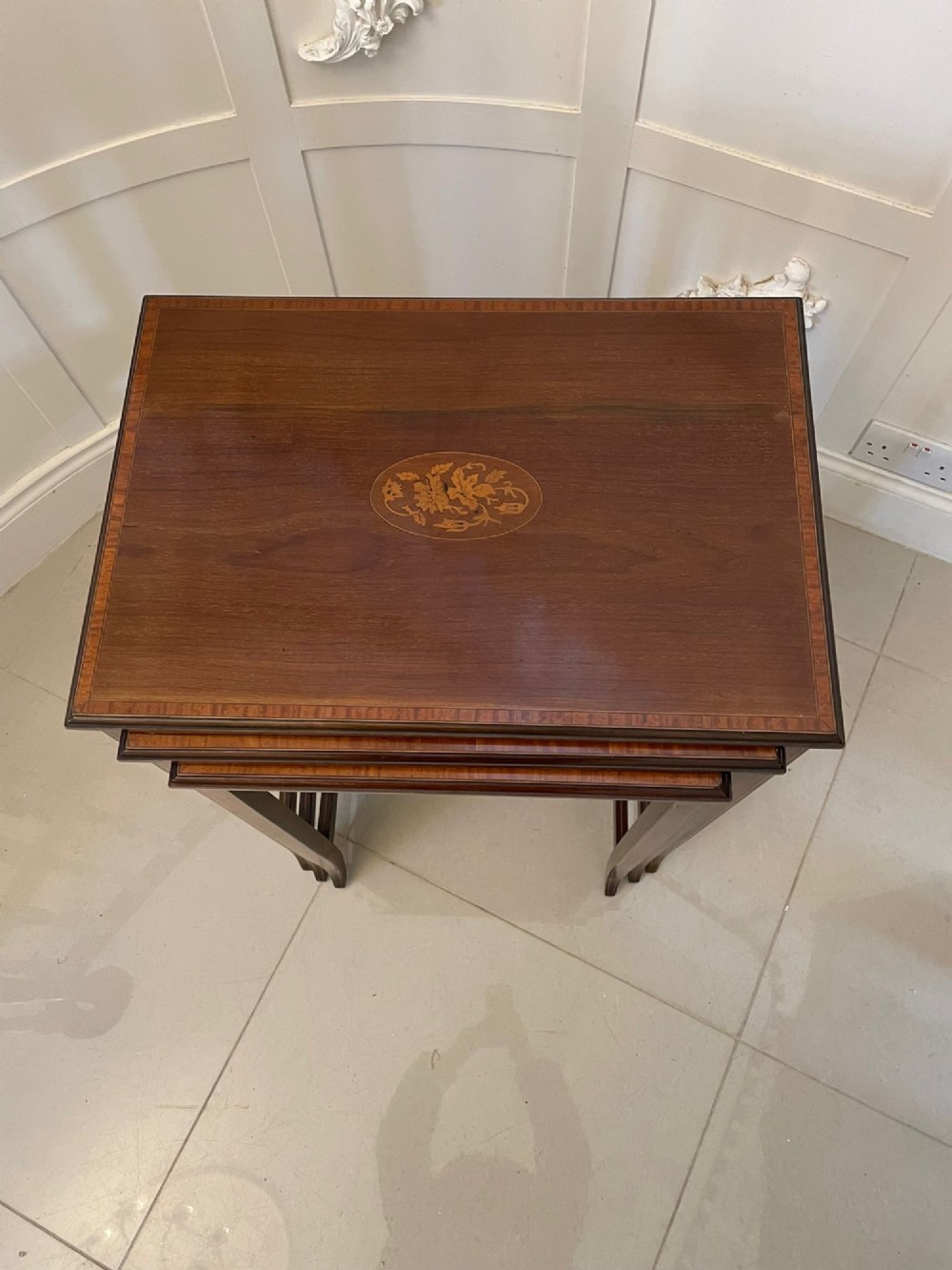 A set of three graduated mahogany nesting tables with central oval satinwood inlays and slender square legs. View V