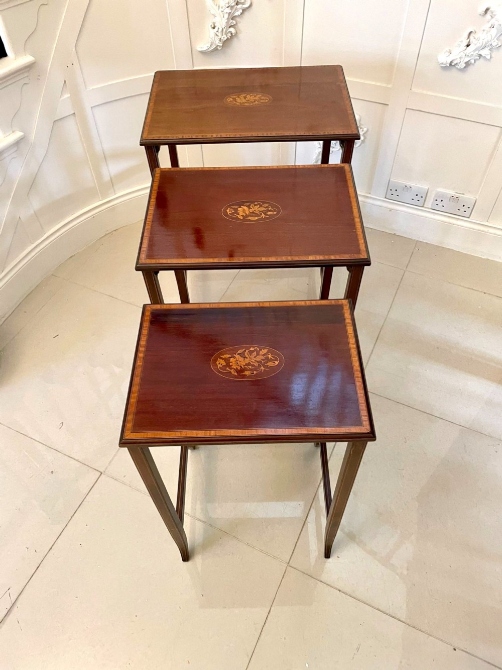 A set of three graduated mahogany nesting tables with central oval satinwood inlays and slender square legs. View VI