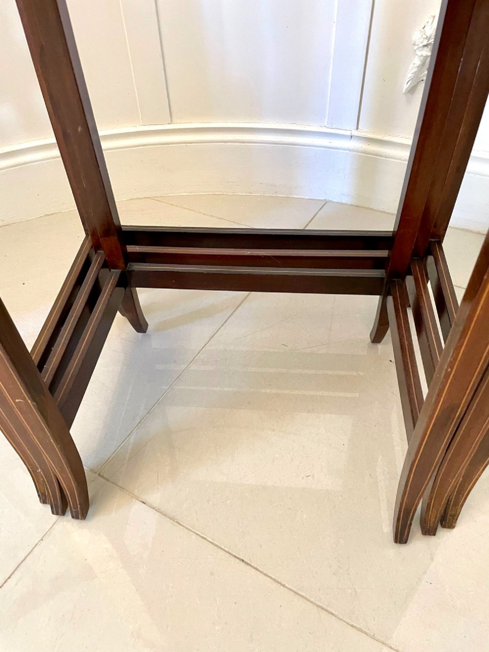 A set of three graduated mahogany nesting tables with central oval satinwood inlays and slender square legs. View VII