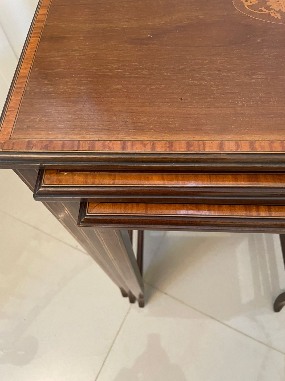 A set of three graduated mahogany nesting tables with central oval satinwood inlays and slender square legs. View X
