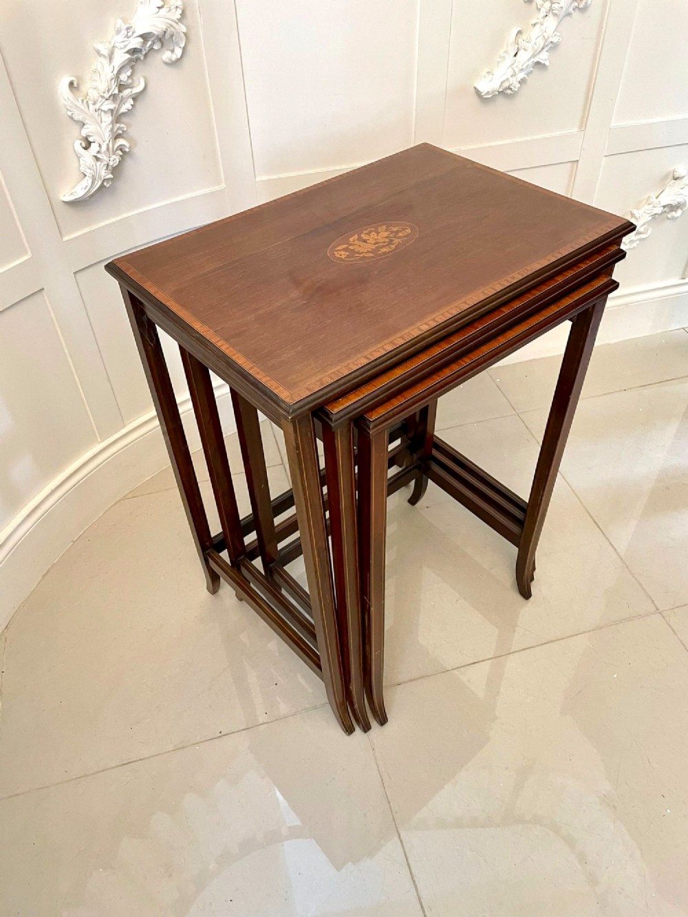 A set of three graduated mahogany nesting tables with central oval satinwood inlays and slender square legs. View XII