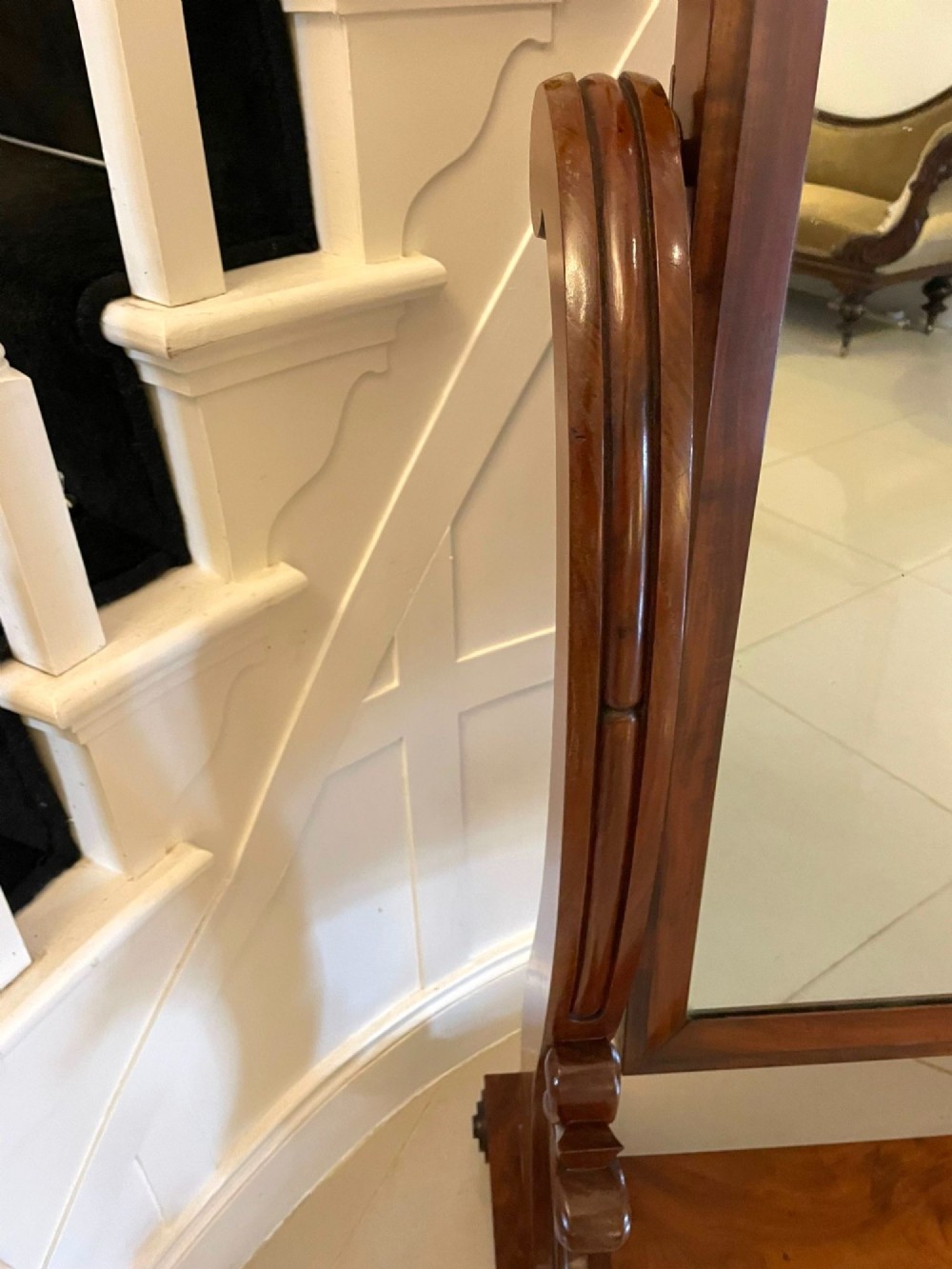 A Victorian mahogany cheval mirror featuring a rectangular swinging frame mounted between curved upright supports on a solid plinth base. View VI