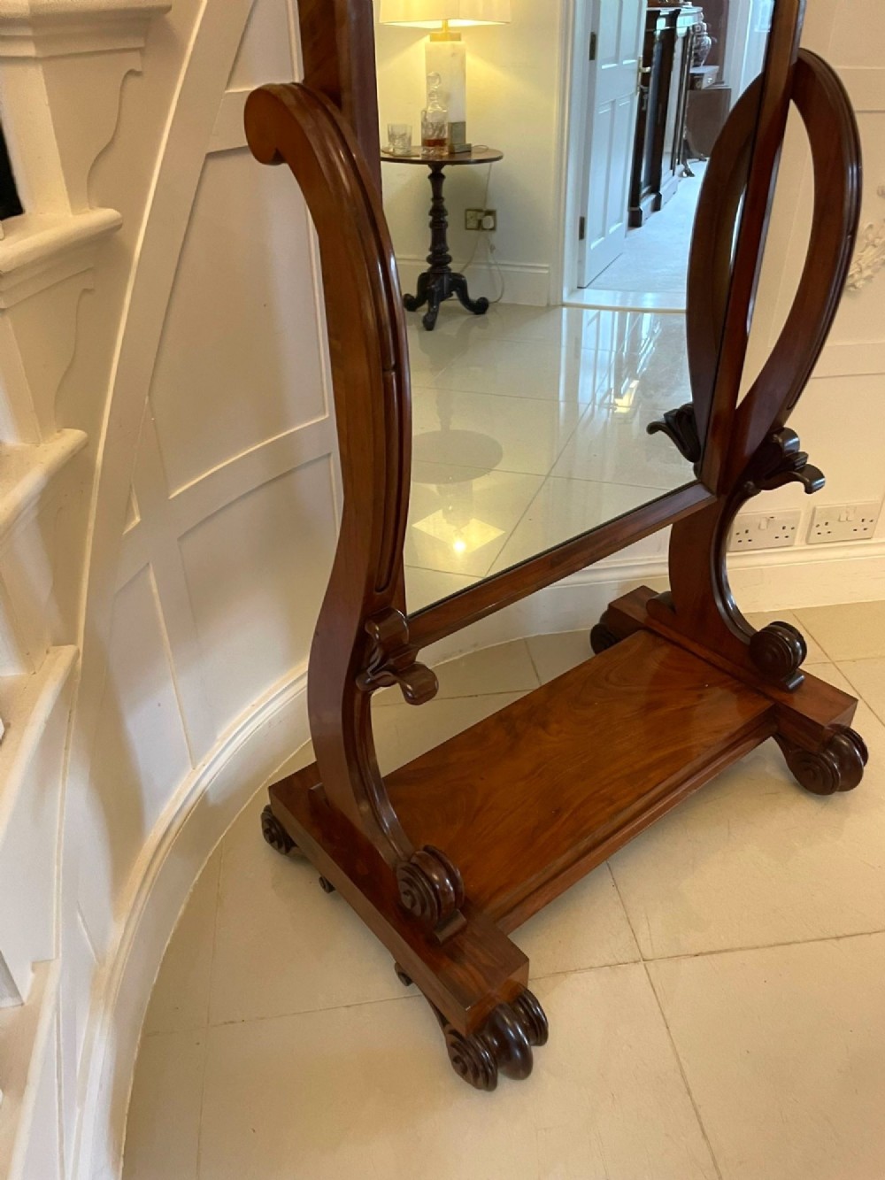 A Victorian mahogany cheval mirror featuring a rectangular swinging frame mounted between curved upright supports on a solid plinth base. View X