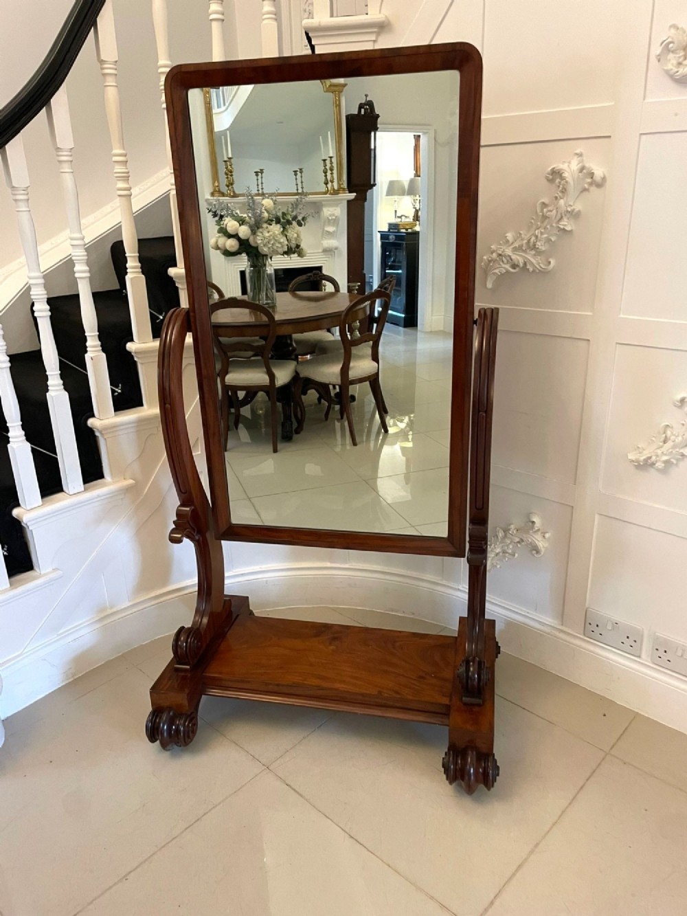 A Victorian mahogany cheval mirror featuring a rectangular swinging frame mounted between curved upright supports on a solid plinth base.