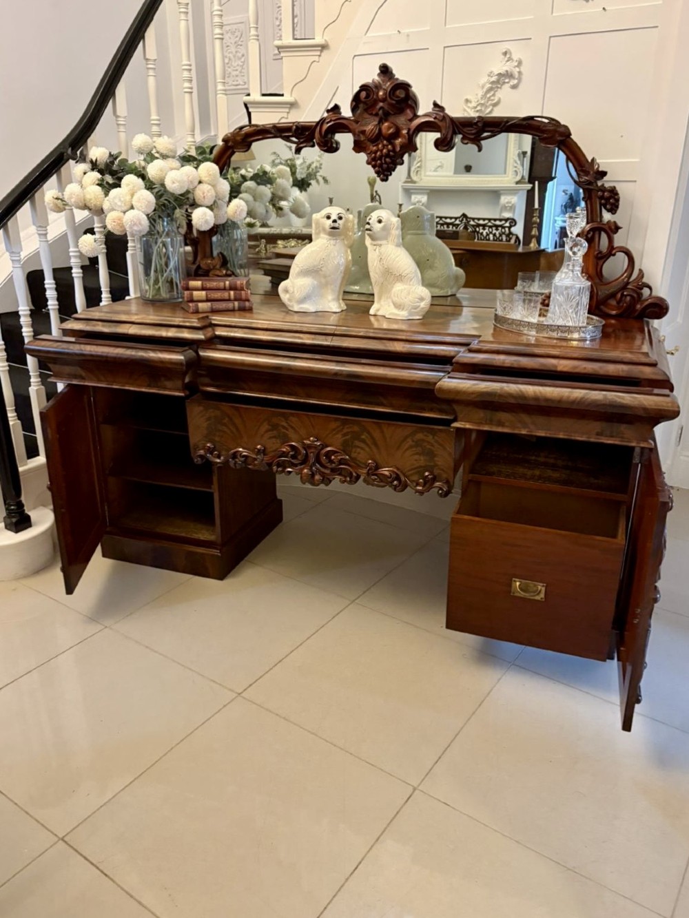 An antique Victorian carved mahogany sideboard featuring twin pedestal bases with carved scroll mouldings and a large arched mirror-backed top frame. View IV
