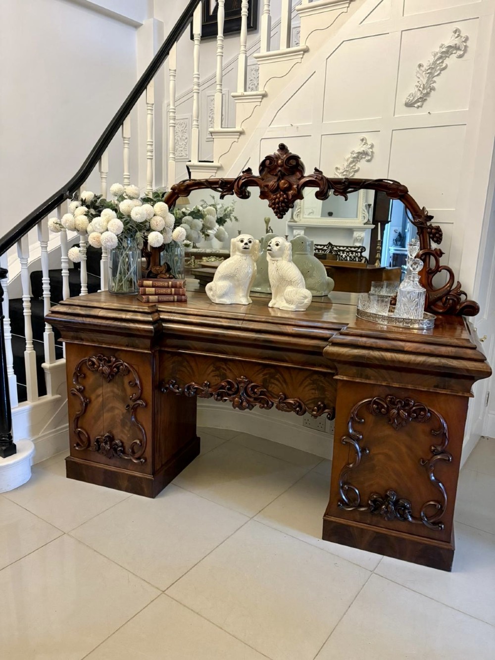 An antique Victorian carved mahogany sideboard featuring twin pedestal bases with carved scroll mouldings and a large arched mirror-backed top frame. View V
