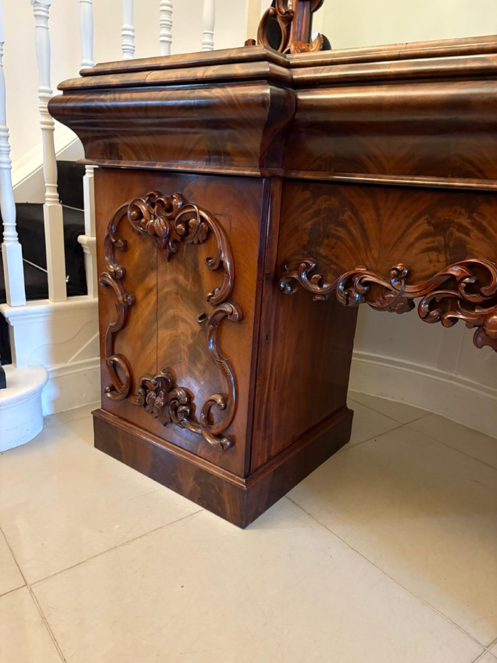 An antique Victorian carved mahogany sideboard featuring twin pedestal bases with carved scroll mouldings and a large arched mirror-backed top frame. View VI