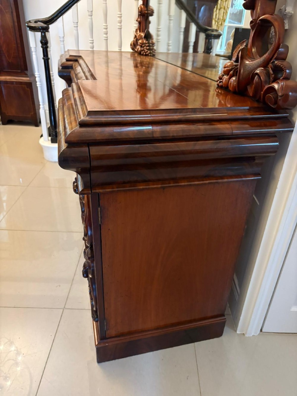 An antique Victorian carved mahogany sideboard featuring twin pedestal bases with carved scroll mouldings and a large arched mirror-backed top frame. View XIV