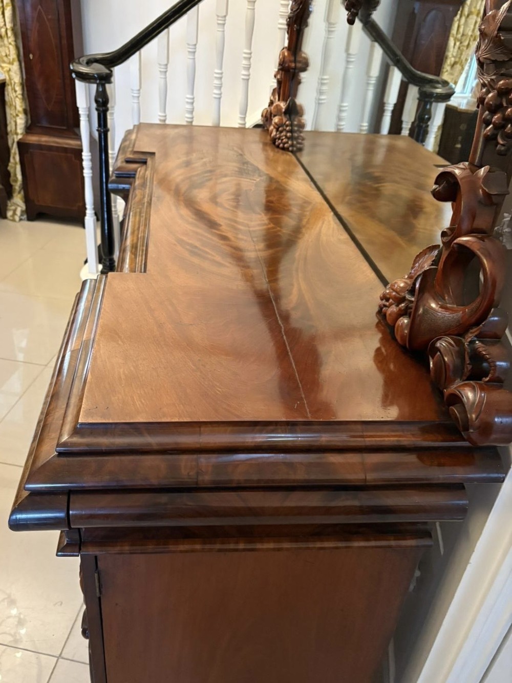An antique Victorian carved mahogany sideboard featuring twin pedestal bases with carved scroll mouldings and a large arched mirror-backed top frame. View XV