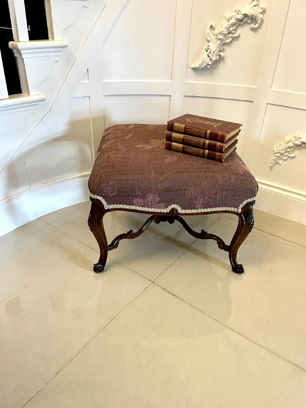 An antique Victorian stool featuring carved dark rosewood cabriole legs and a low rectangular padded seat upholstered in a floral pattern fabric. View II
