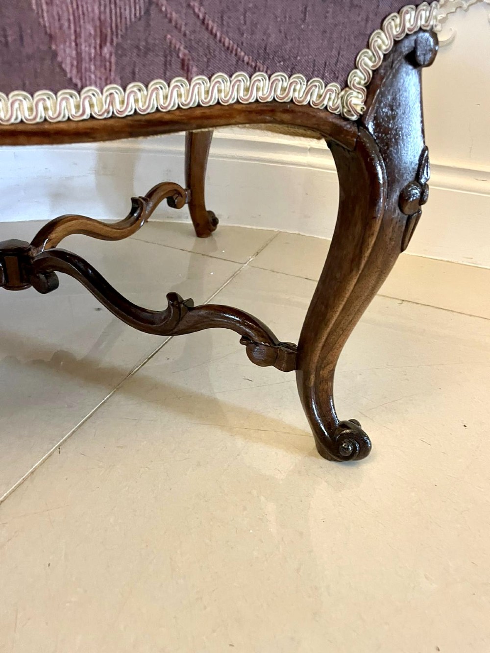 An antique Victorian stool featuring carved dark rosewood cabriole legs and a low rectangular padded seat upholstered in a floral pattern fabric. View III
