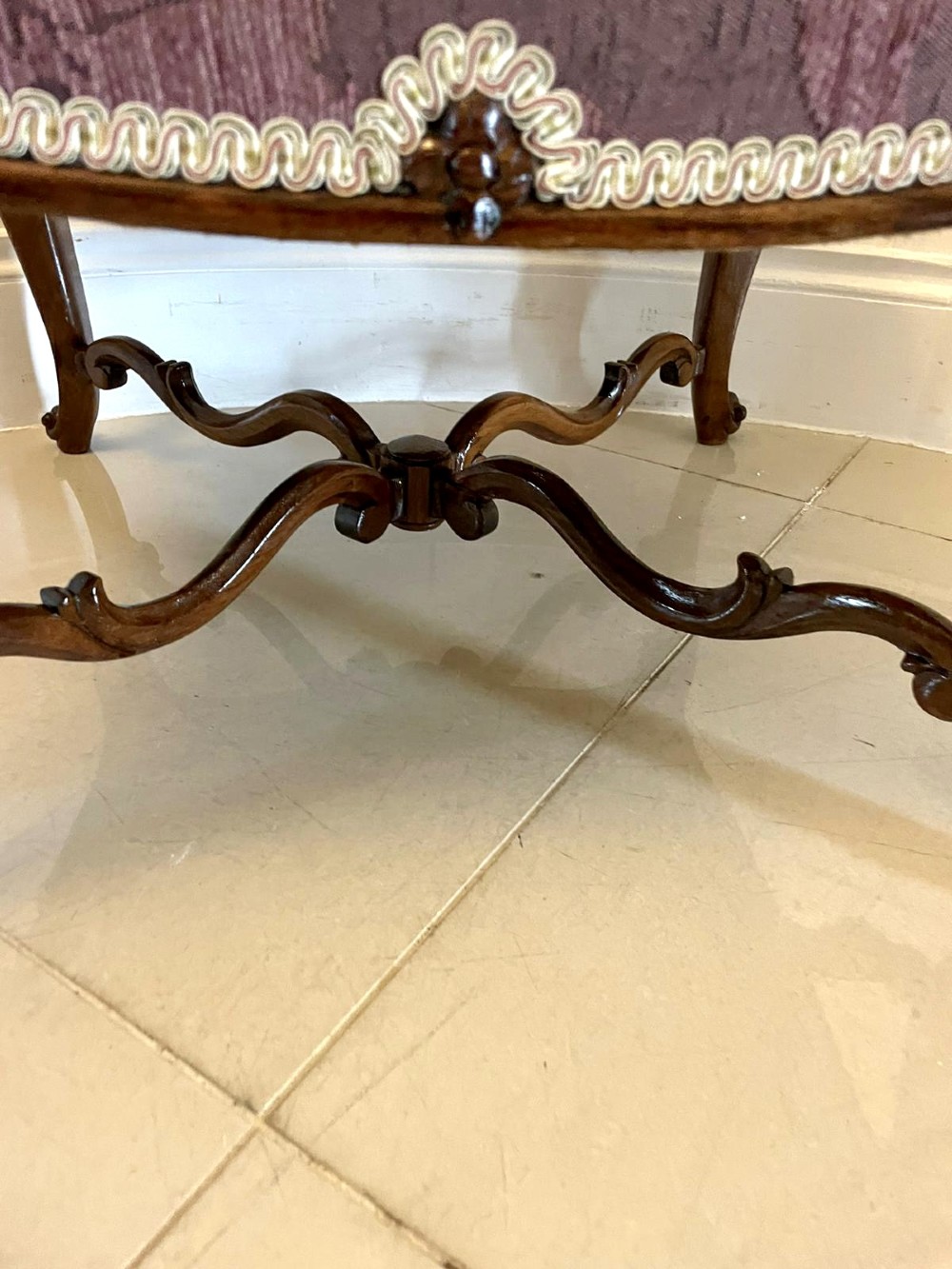An antique Victorian stool featuring carved dark rosewood cabriole legs and a low rectangular padded seat upholstered in a floral pattern fabric. View IV