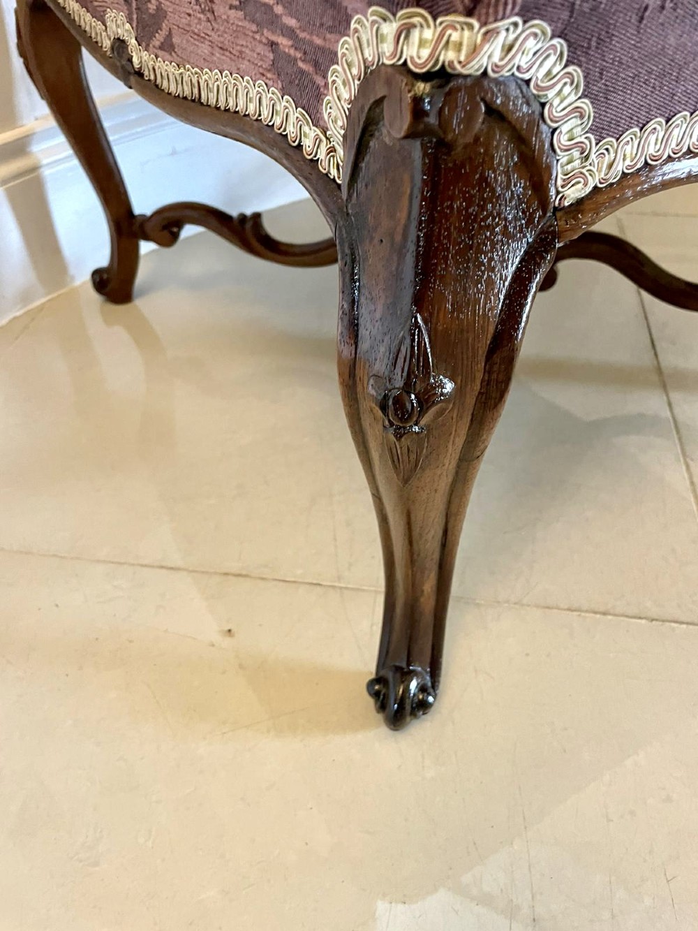 An antique Victorian stool featuring carved dark rosewood cabriole legs and a low rectangular padded seat upholstered in a floral pattern fabric. View V
