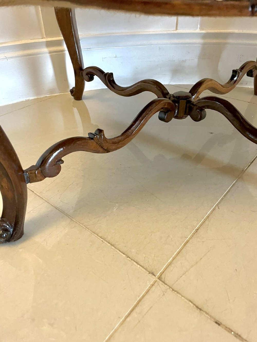 An antique Victorian stool featuring carved dark rosewood cabriole legs and a low rectangular padded seat upholstered in a floral pattern fabric. View VI