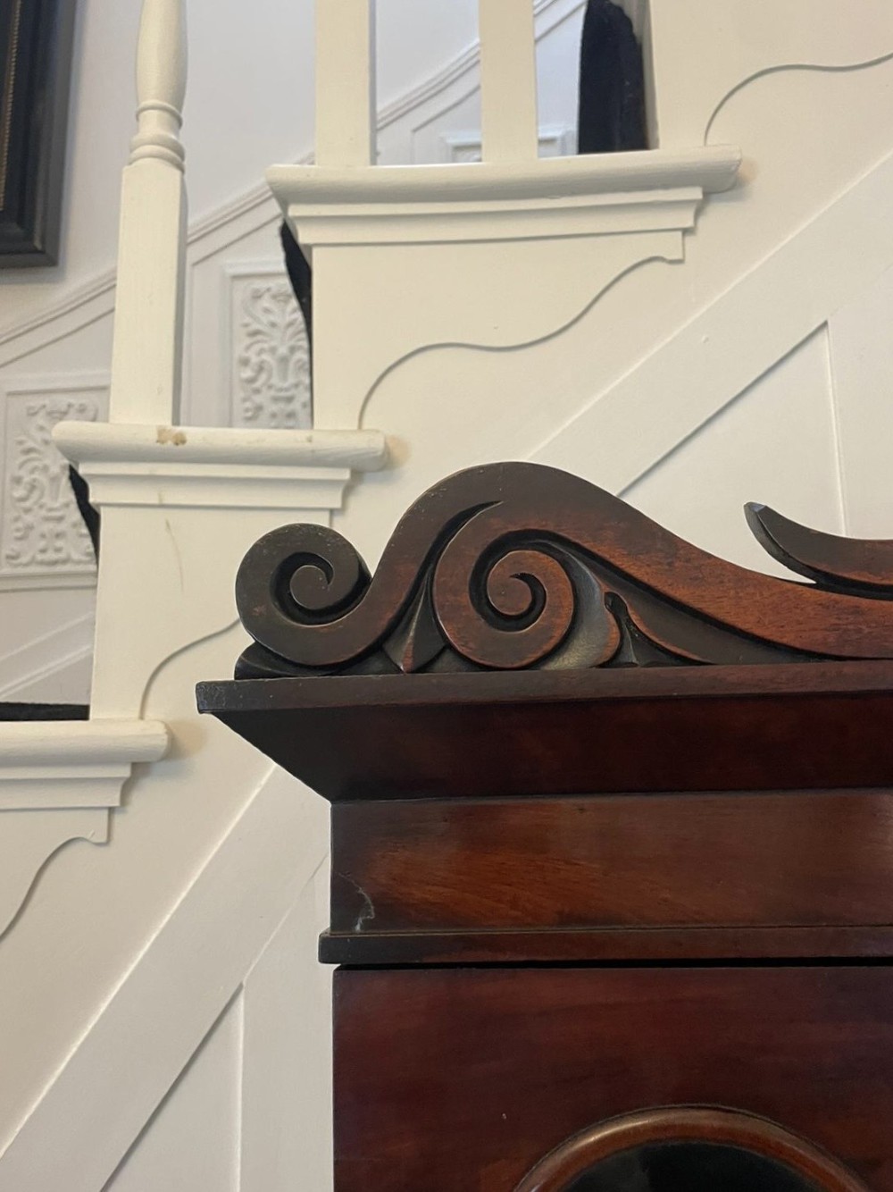 An antique Regency mahogany secretaire bookcase featuring a carved scroll pediment, glazed upper doors, a fall-front desk drawer, and a lower two-door cupboard. View VIII