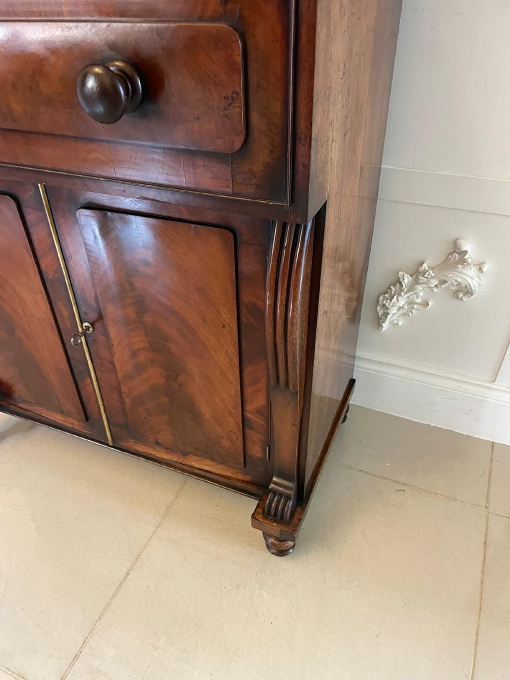 An antique Regency mahogany secretaire bookcase featuring a carved scroll pediment, glazed upper doors, a fall-front desk drawer, and a lower two-door cupboard. View XIII