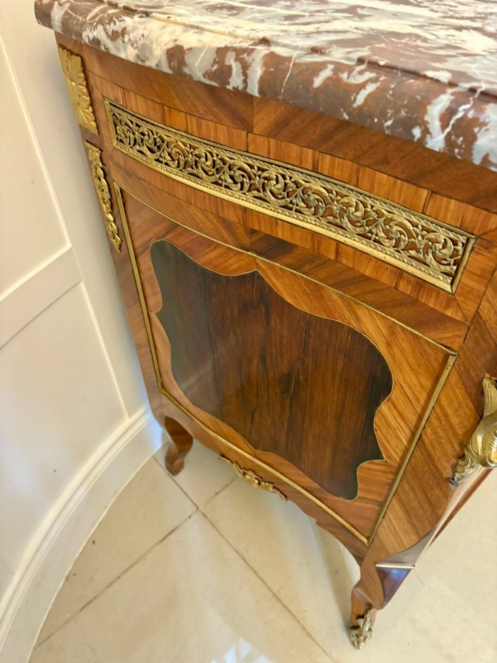 An antique French style commode chest featuring a dark grey veined marble top, decorative walnut veneers, cast brass mounts, and cabriole legs. View II