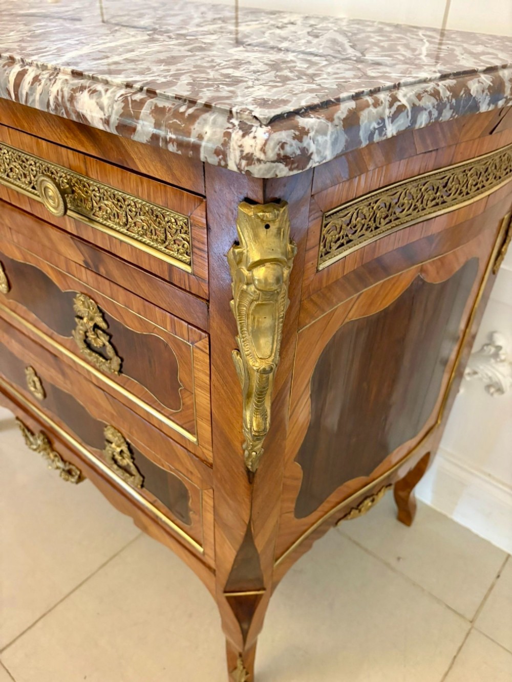 An antique French style commode chest featuring a dark grey veined marble top, decorative walnut veneers, cast brass mounts, and cabriole legs. View VII