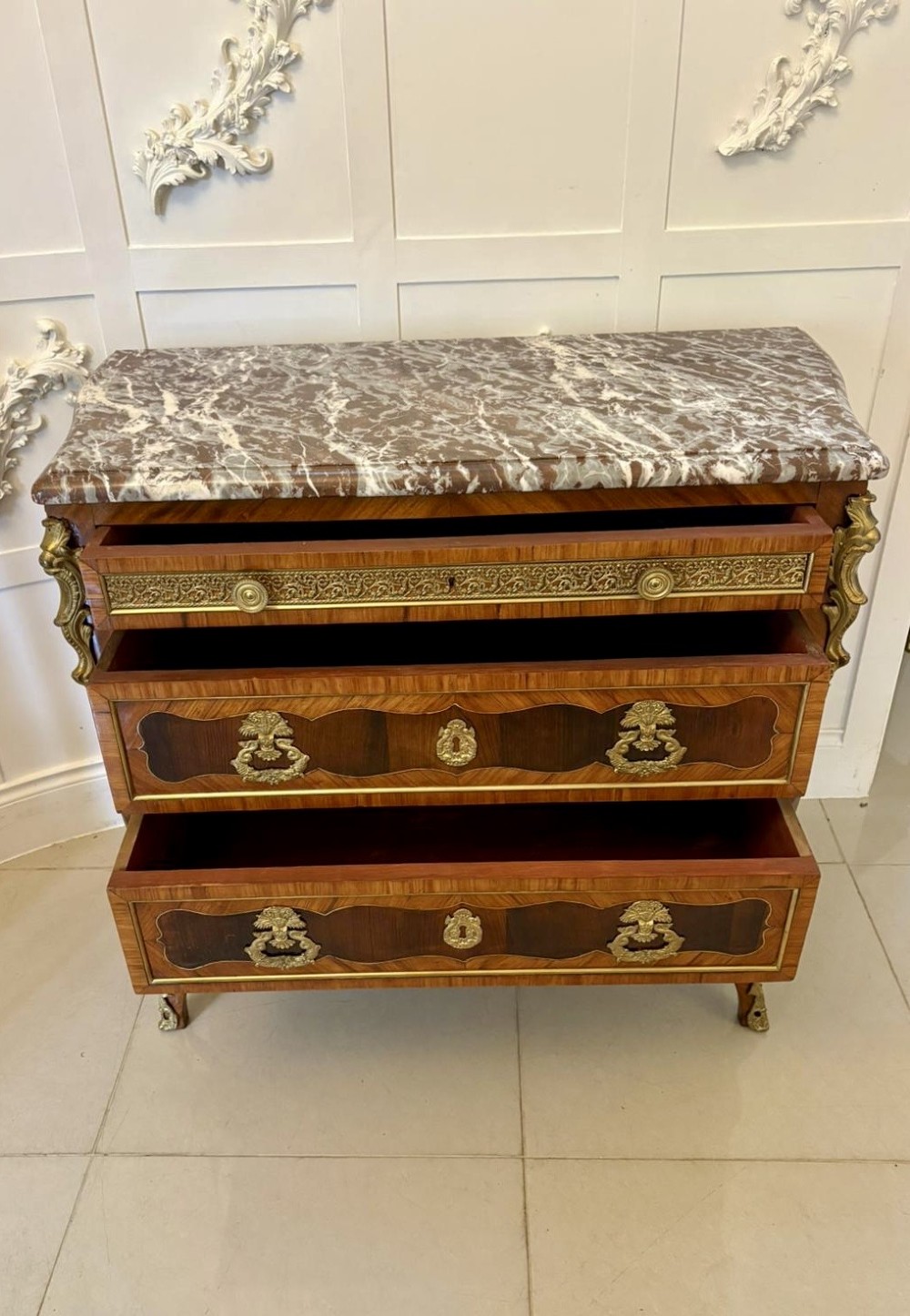 An antique French style commode chest featuring a dark grey veined marble top, decorative walnut veneers, cast brass mounts, and cabriole legs. View VIII