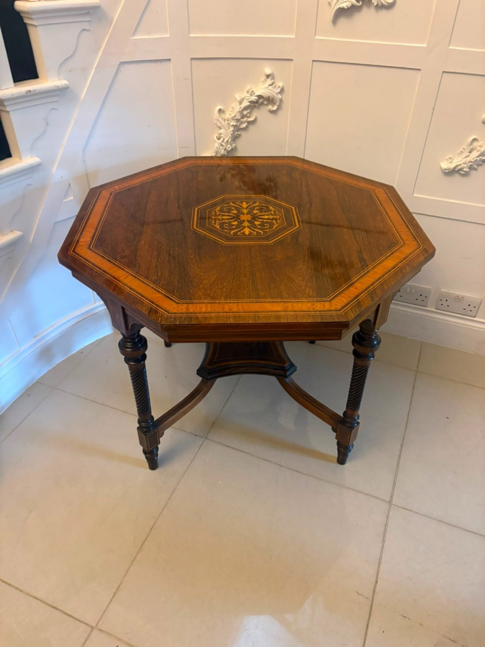 An octagonal Victorian rosewood centre table with intricate central marquetry inlay, crossbanded borders, and spiral turned legs joined by a lower stretcher.