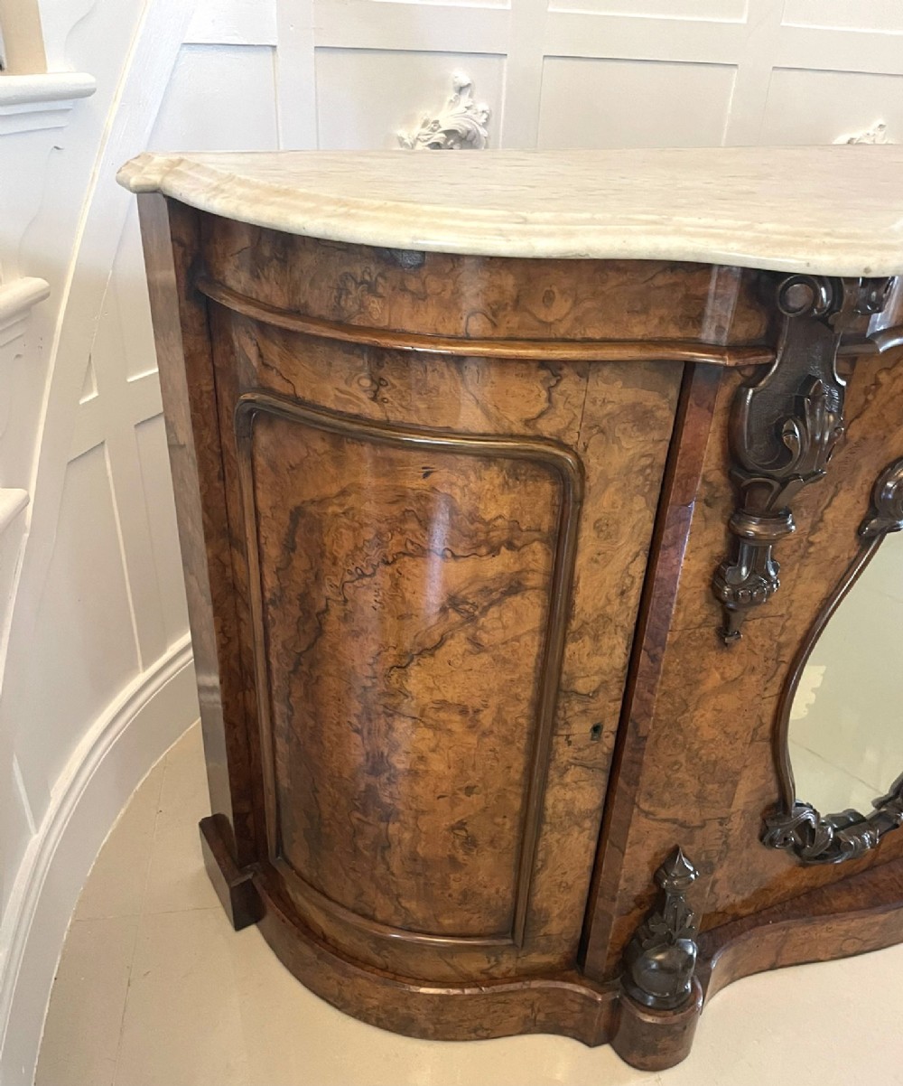 A Victorian burr walnut credenza featuring a serpentine white marble top above two central oval mirrored doors and carved scroll accents. View III