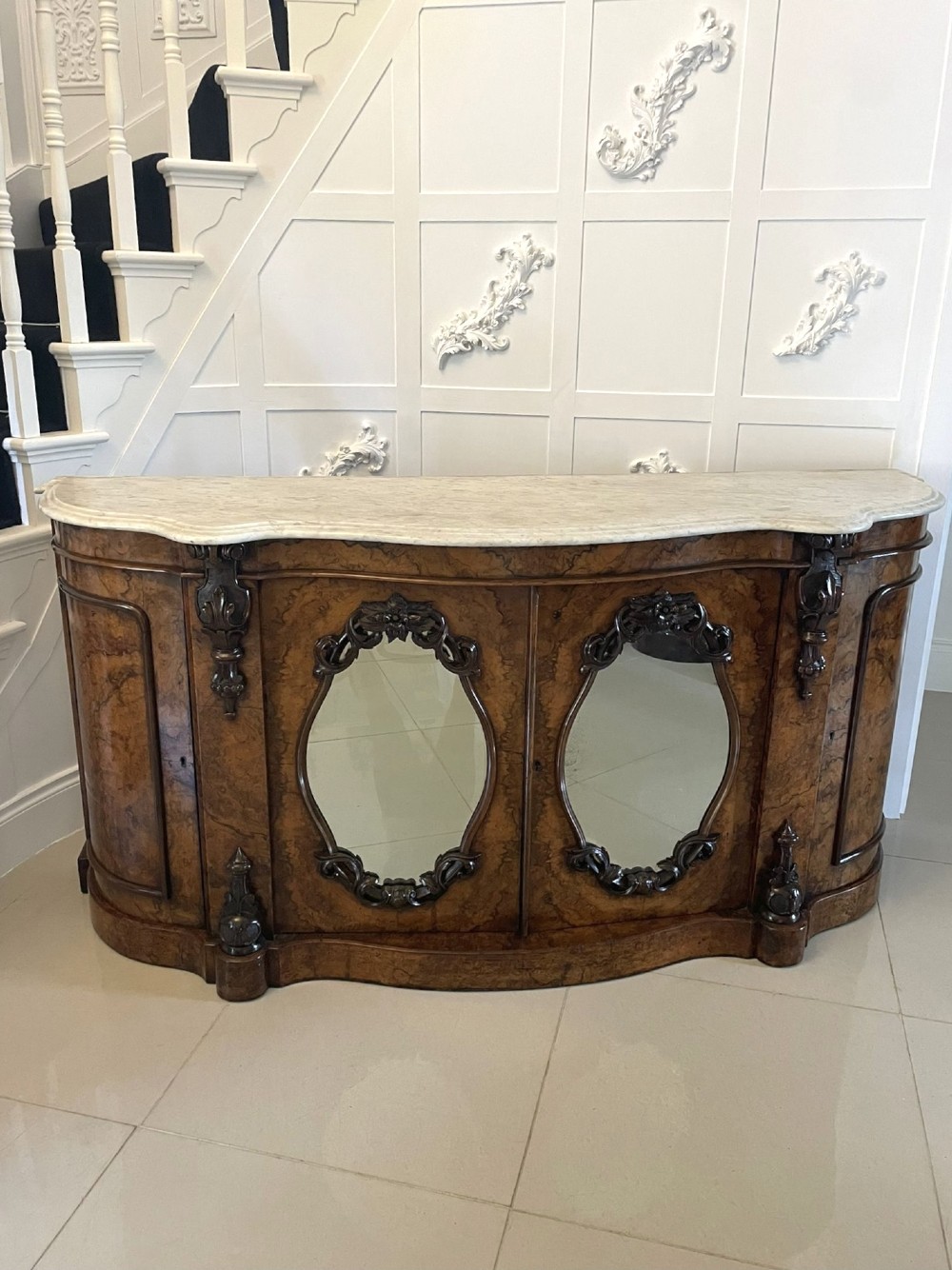 A Victorian burr walnut credenza featuring a serpentine white marble top above two central oval mirrored doors and carved scroll accents. View XI
