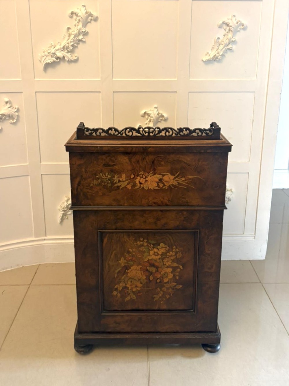 A Victorian burr walnut piano top davenport desk featuring floral marquetry, side drawers with turned wooden knobs, and carved supports. View VI
