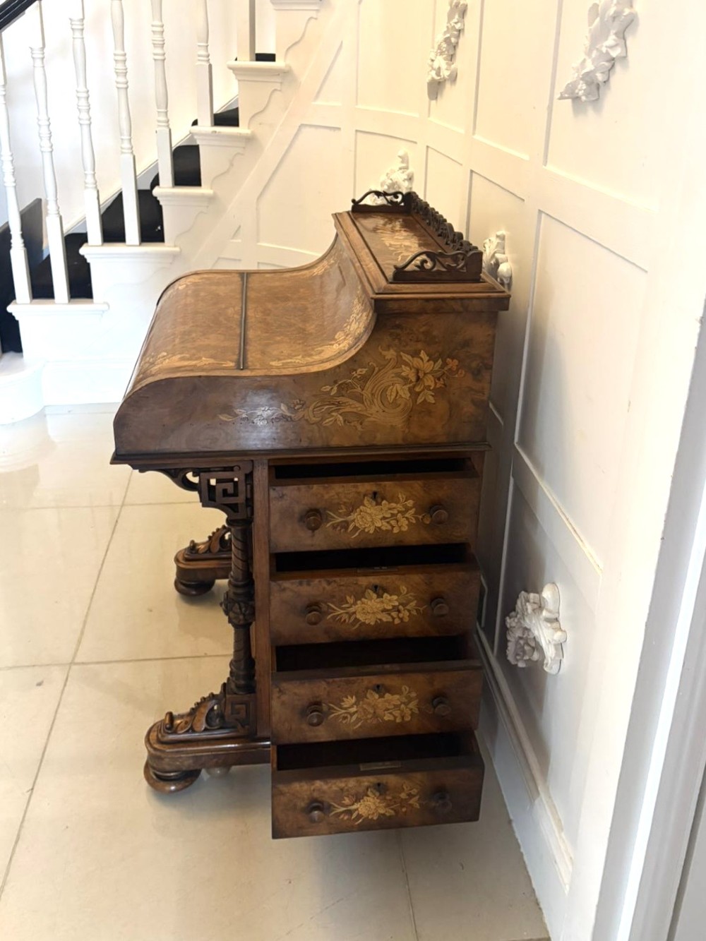 A Victorian burr walnut piano top davenport desk featuring floral marquetry, side drawers with turned wooden knobs, and carved supports. View IX
