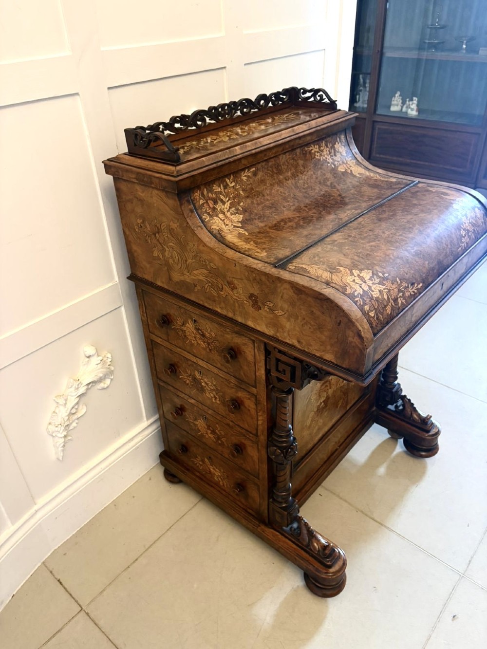 A Victorian burr walnut piano top davenport desk featuring floral marquetry, side drawers with turned wooden knobs, and carved supports. View X