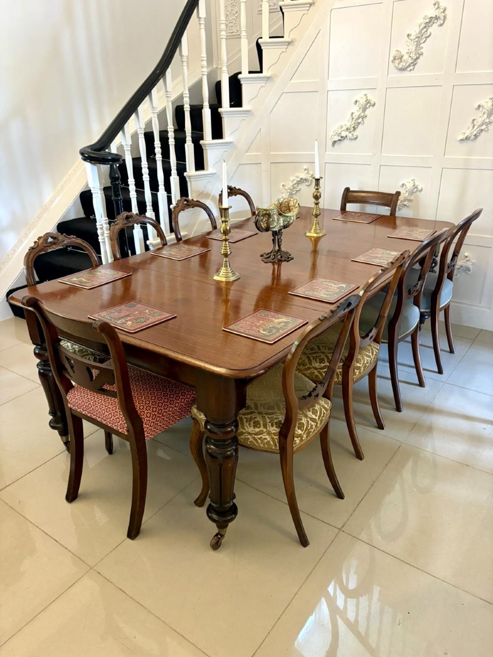 A large Victorian extending mahogany dining table featuring rounded corners, turned legs, brass castors, and a polished dark wood surface. View VI