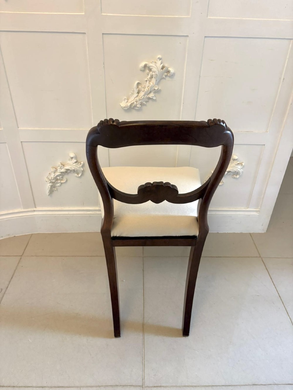 A set of ten antique English Regency mahogany dining chairs with carved balloon backs, cream upholstered seats, and turned front legs. View IV