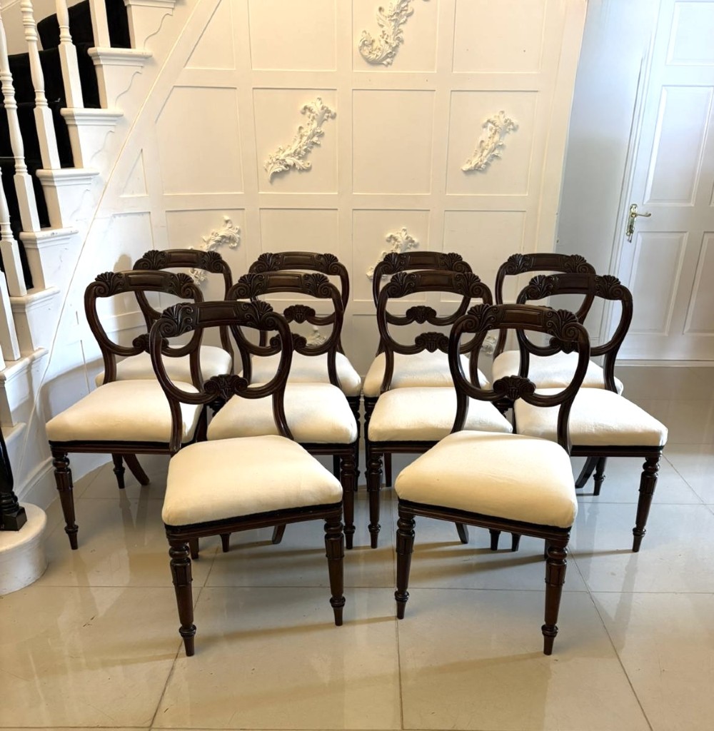 A set of ten antique English Regency mahogany dining chairs with carved balloon backs, cream upholstered seats, and turned front legs.