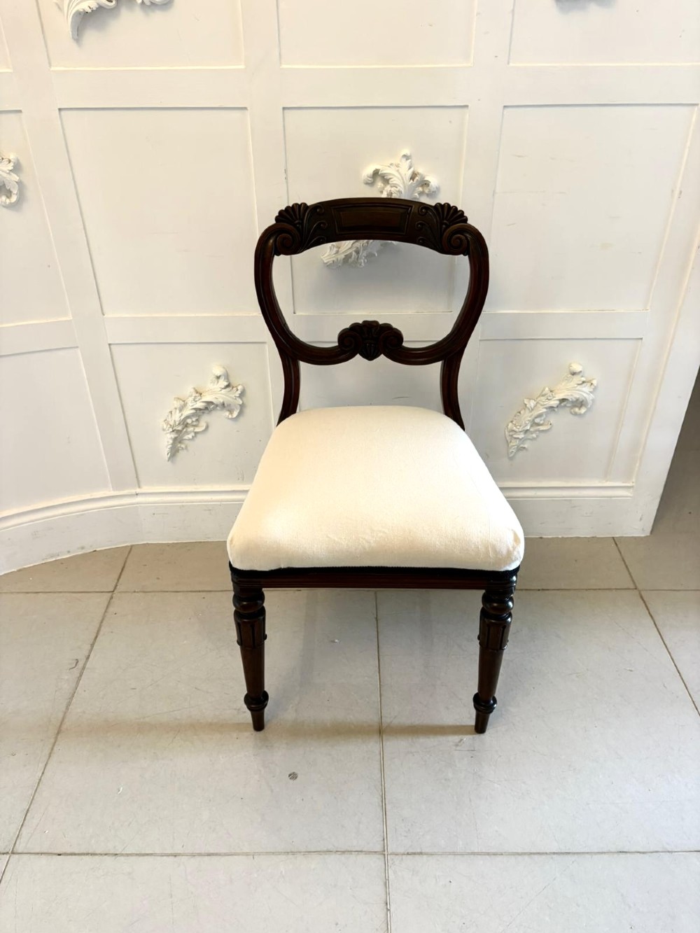 A set of ten antique English Regency mahogany dining chairs with carved balloon backs, cream upholstered seats, and turned front legs. View XI