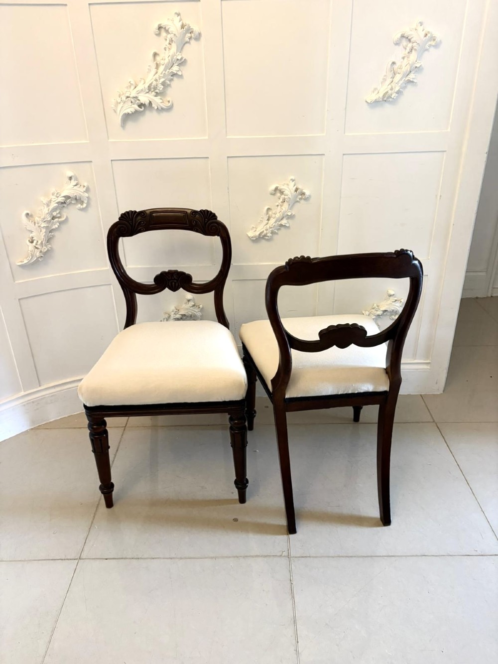 A set of ten antique English Regency mahogany dining chairs with carved balloon backs, cream upholstered seats, and turned front legs. View XII